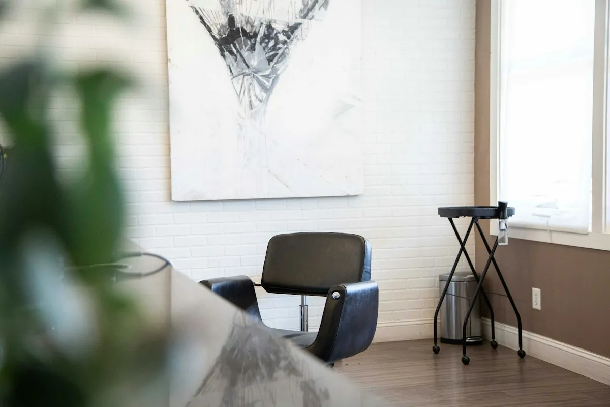 A salon chair by a window, in front of a white brick wall